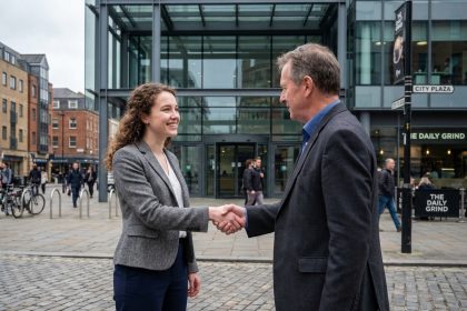 Femme jeune en blazer serre la main d'un mentor homme devant un bâtiment